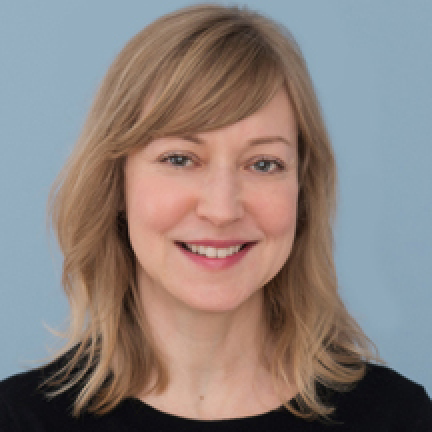 Headshot of Janis Sayer who has blonde hair and blue eyes. She smiles at the camera on a light blue background.