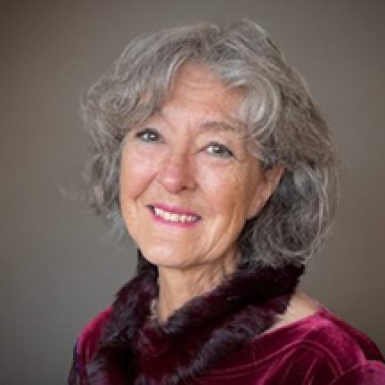 Headshot of Kathleen West. She has grey hair and wears a red blouse and scarf.