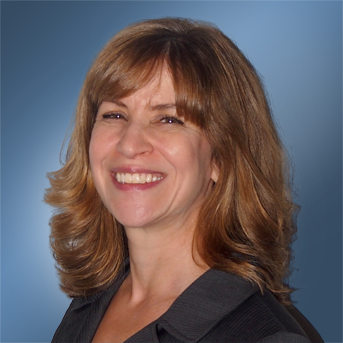 The image shows a headshot of Susan Pickett with shoulder-length light-brown hair with bangs and smiling. They are dressed in a dark collared top.